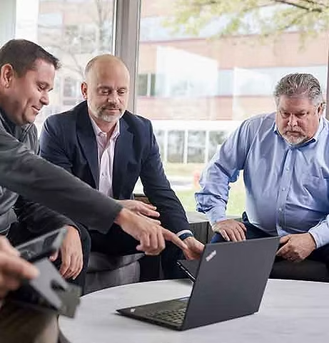 Colleagues sharing ideas around a laptop
